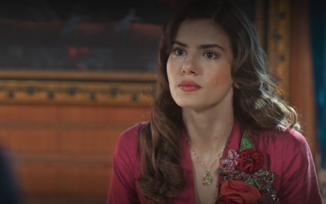 A atriz Camila Queiroz está com cabelos soltos e usa vestido vermelho em cena como Marê na novela Amor Perfeito