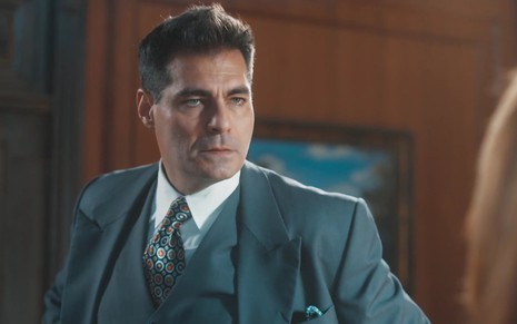 O ator Thiago Lacerda usa terno, colete e gravata e está sério em cena como Gaspar na novela Amor Perfeito