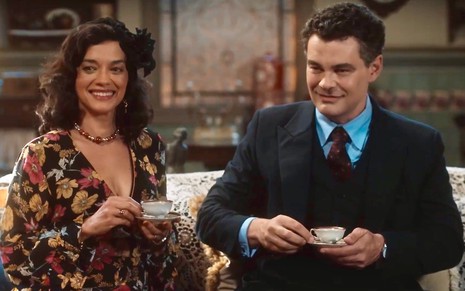 Ana Cecília Costa e Carmo Dalla Cecchia estão sentados lado a lado em um sofá e seguram xícaras em cena de Amor Perfeito