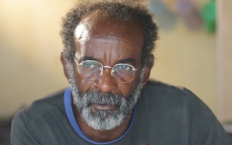 Wilson Rabelo tem a barba longa, usa óculos e veste uma camisa preta; ele olha para o lado, sério, em foto de divulgação de Bacurau (2019)