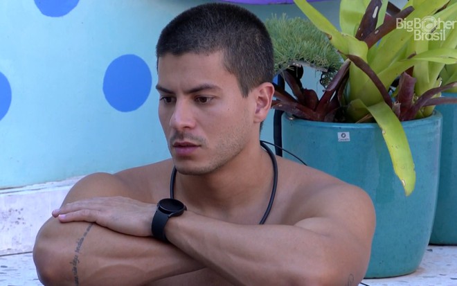 Arthur Aguiar tem o semblante pensativo; ele está com os braços cruzados enquanto relaxa na hidromassagem