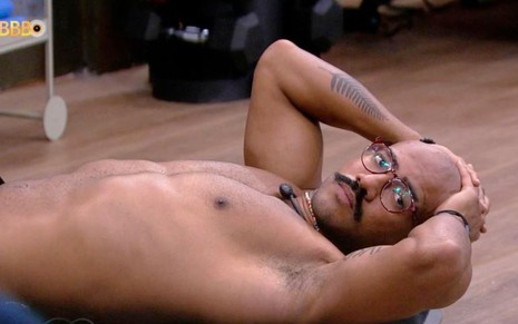 Ricardo Camargo, sem camisa, deitado no chão da academia do BBB 23