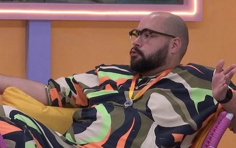 O ator Tiago Abravanel com um pijama colorido sentado em uma poltrona na área externa do Big Brother Brasil 22