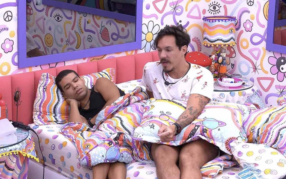 Deitado em uma cama, Vinícius ouve Eliezer, sentado, no quarto Lollipop do Big Brother Brasil
