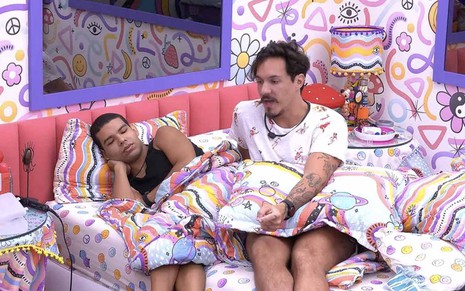 Deitado em uma cama, Vinícius ouve Eliezer, sentado, no quarto Lollipop do Big Brother Brasil