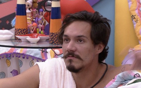 Eliezer Netto sentado no chão do quarto lollipop do Big Brother Brasil 22