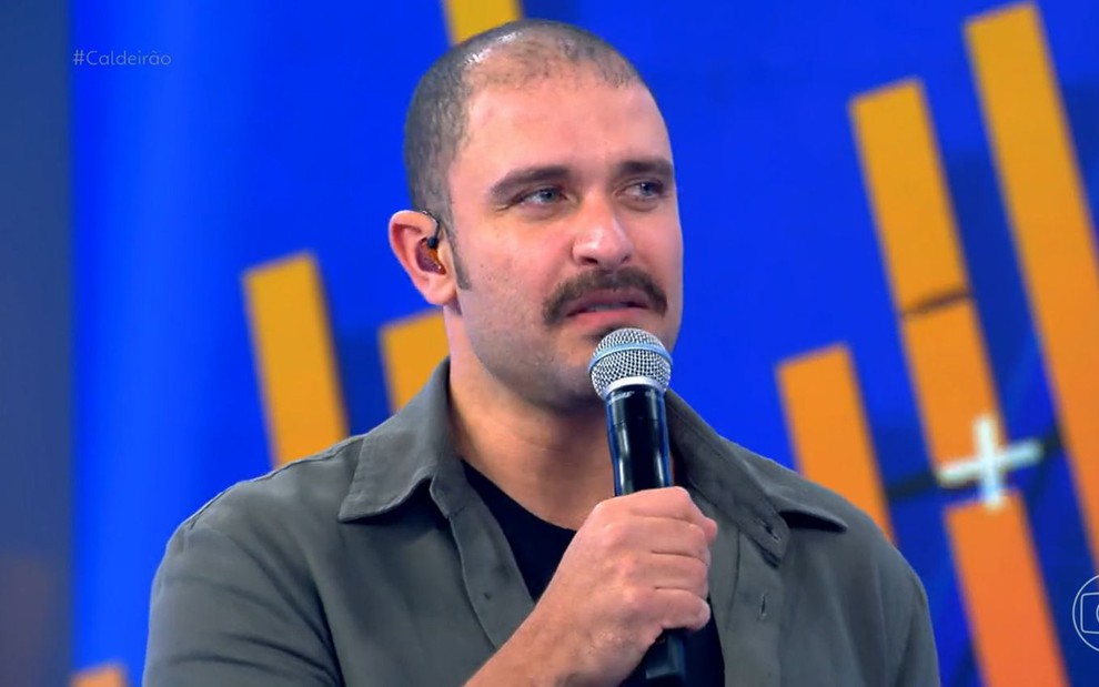 Diogo Nogueira segura o microfone; ele tem um bigode cheio