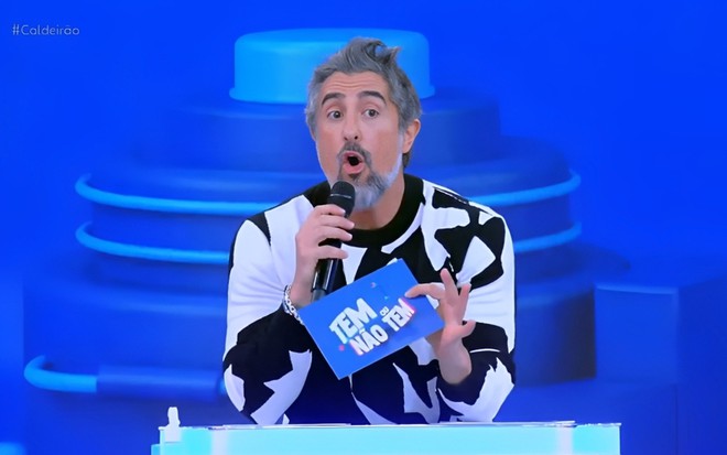 Marcos Mion faz um "O" com a boca, como se estivesse surpreso, no cenário do Tem ou Não Tem