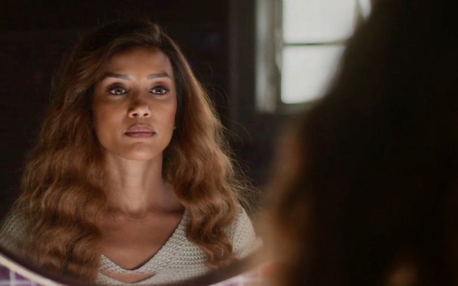 A atriz Taís Araujo está diante de um espelho em cena como a personagem Clarice de Cara e Coragem