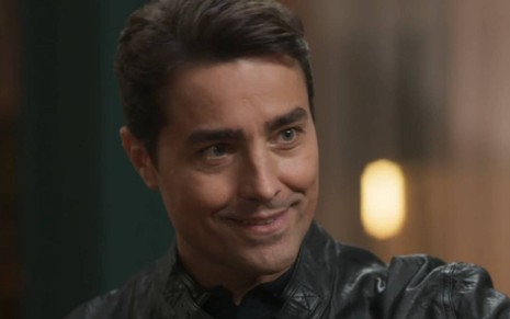 O ator Ricardo Pereira em cena de Cara e Coragem na qual usa uma jaqueta preta caracterizado como Danilo
