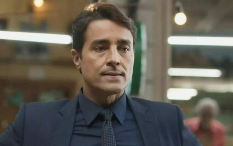 O ator Ricardo Pereira usa terno, camisa e gravata escuros m cena de Cara e Coragem, novela das sete da Globo