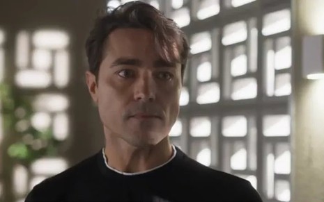 O ator Ricardo Pereira está com camisa preta e olha sério para a frente durante gravação da novela Cara e Coragem