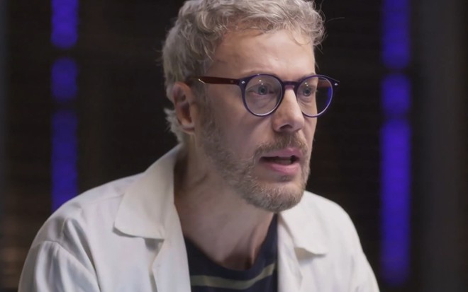 Jonathan (Guilherme Weber) de jaleco de cientista e expressão séria em cena de Cara e Coragem