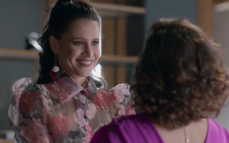 A atriz Mel Lisboa sorri para Claudia Di Moura, que está de costas na imagem, em gravação de cena da novela Cara e Coragem
