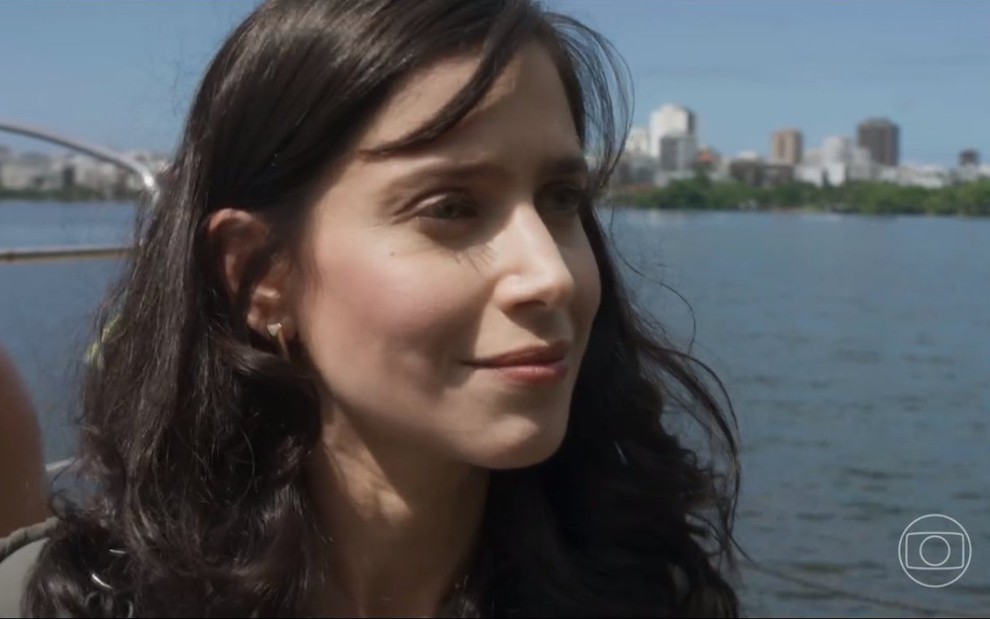 A atriz Mel Lisboa está com os cabelos soltos em gravação de Cara e Coragem perto de uma lagoa