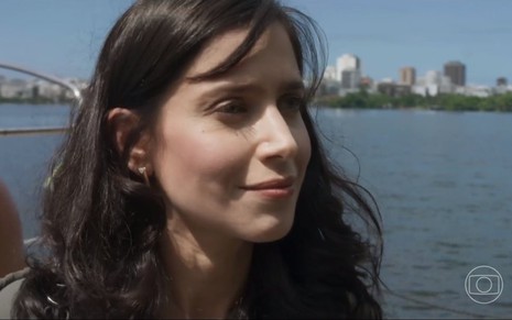 A atriz Mel Lisboa está com os cabelos soltos em gravação de Cara e Coragem perto de uma lagoa