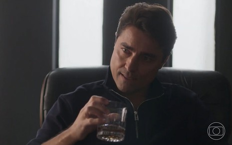 Danilo (Ricardo Pereira) com um copo de uísque na mão em cena de Cara e Coragem