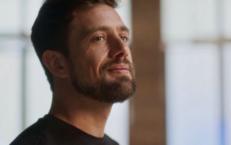 O ator Rafael Cardoso usa camiseta preta e está em close em cena da novela das sete da Globo, Cara e Coragem