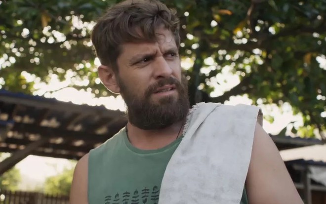 O ator Alejandro Claveaux está com uma regata verde e um pano no ombro em cena de Cara e Coragem