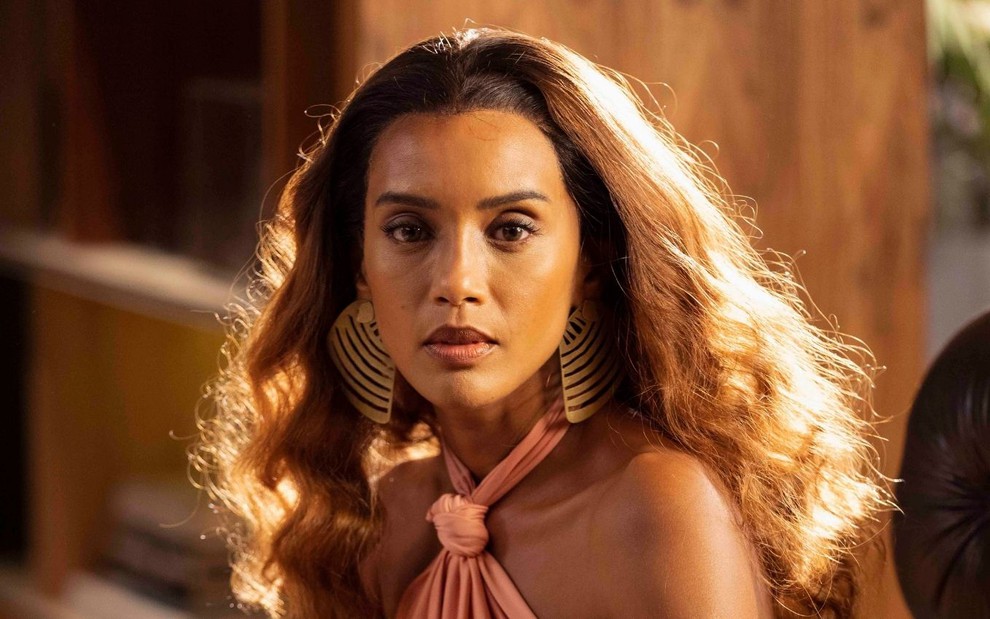 Taís Araujo caracterizada como Clarice; atriz usa blusa frente única e tem os cabelos esvoaçantes em ensaio de divulgação de Cara e Coragem