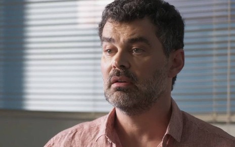 Ator Carmo Dalla Vecchia olha para frente com cara de sério em cena de Cara e Coragem, novela das sete da Globo