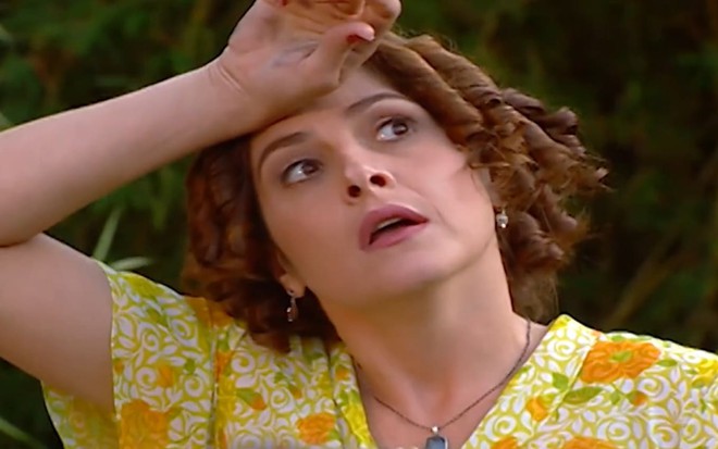 Drica Moraes tem os cabelos curtos e castanhos, na altura dos ombros, e usa um vestido florido. Ela está com os olhos arregalados e a boca aberta em cena de Chocolate com Pimenta