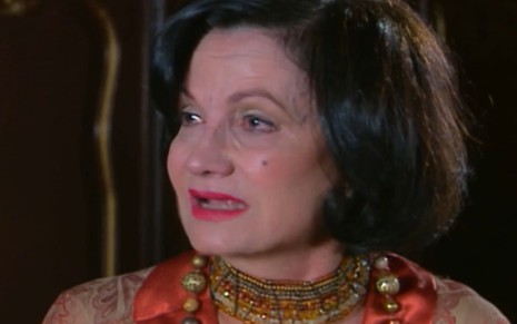 Rosamaria Murtinho caracterizada como Margot em Chocolate com Pimenta; ela usa uma maquiagem forte, tem os cabelos curtos e usa um vestido vermelho; o semblante está perturbado