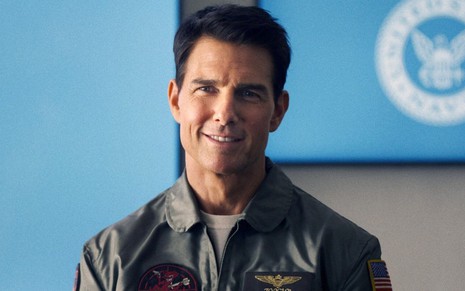 Tom Cruise sorri e veste uniforme militar em cena do filme Top Gun: Maverick, lançado em 2022