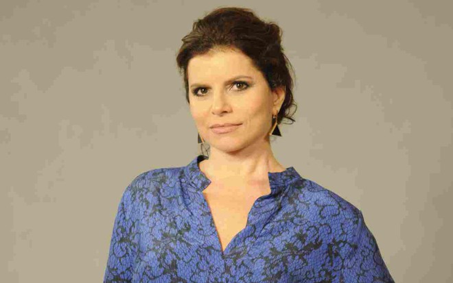 A atriz Debora Bloch com uma blusa azul posando para foto