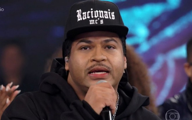 De boné e capuz, Robson Nunes caracterizado como o rapper Mano Brown no palco do Domingão com Huck, da Globo, neste domingo (28)
