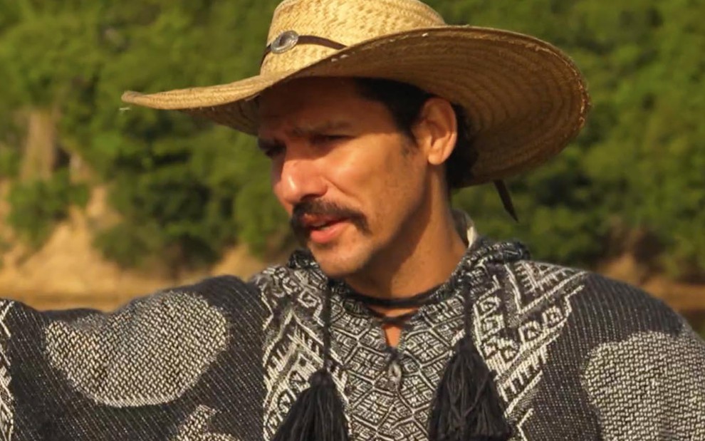 O ator Guito com um poncho nos bastidores de Pantanal em entrevista ao Domingão com Huck