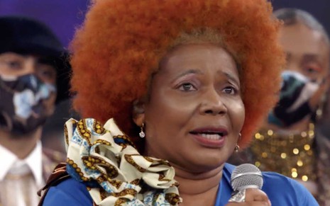 A cantora Margareth Menezes caracterizada como Sandra de Sá com uma peruca ruiva