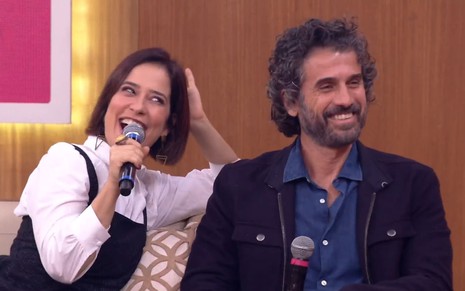 Paloma Duarte sorri, com um microfone na mão, enquanto se curva em direção a Eriberto Leão; o ator dá um leve sorriso, também segurando o microfone, durante o Encontro com Fátima Bernardes