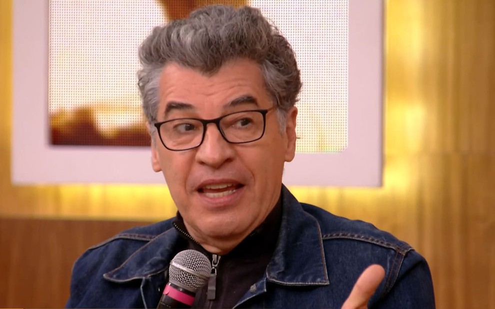 Paulo Betti tem os cabelos grisalhos e usa um óculos preto; ele veste uma blusa preta e uma jaqueta jeans no Encontro com Fátima Bernardes