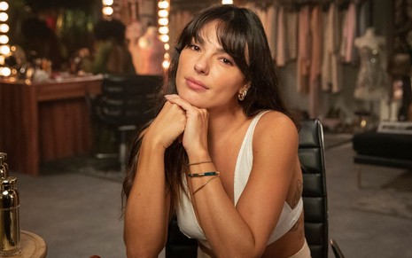 A atriz Isis Valverde veste branco sentada em um camarim na gravação da vinheta de final de ano da Globo