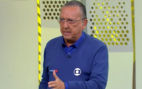 Galvão Bueno com uma blusa azul e calça marrom, no estúdio da Globo em São Paulo