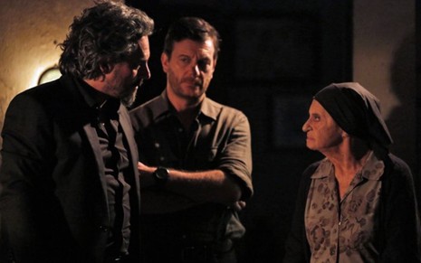José Alfredo (Alexandre Nero) está em pé em frente à Jesuína (Laura Cardoso) e ao lado de Josué (Roberto Birindelli) na casa da idosa em cena de Império