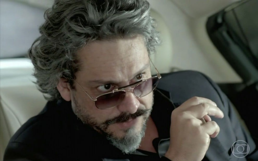 José Alfredo (Alexandre Nero) está de óculos escuro e dentro de carro em cena de Império