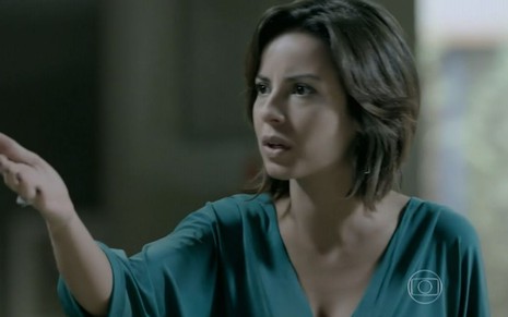 Maria Clara (Andréia Horta) está em pé e gesticula com a mão na sala da mansão dos Medeiros em cena de Império