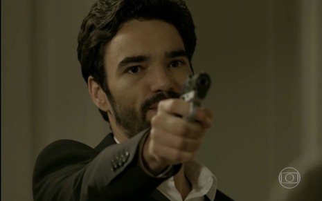Caio Blat grava cena, apontando arma para Leandra Leal, que não aparece na imagem, como José Pedro em Império, da Globo