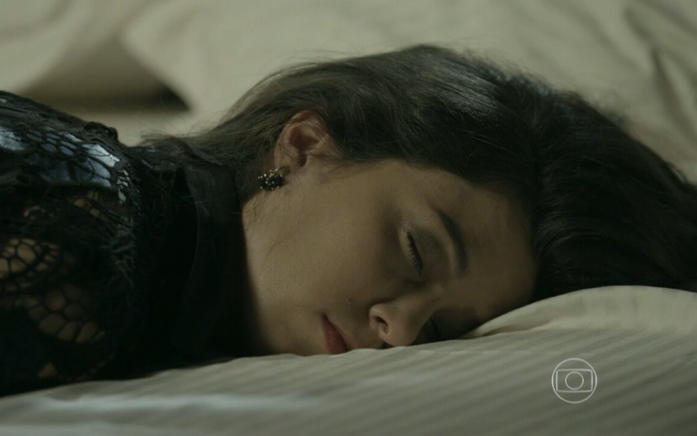 Marjorie Estiano grava vestida de preto e deitada na cama dormindo como Cora de Império