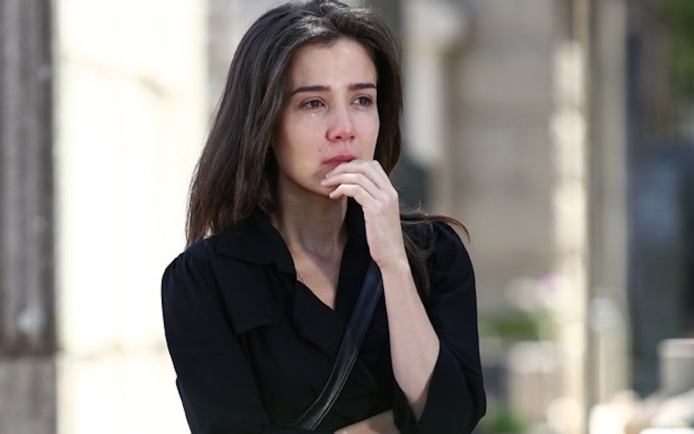A atriz Marjorie Estiano veste preto e tem lágrimas escorrendo pelo rosto em cena gravada em cemitério para a novela Império