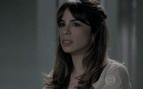 Maria Ribeiro grava de cabelo solto, camisa branca e expressão pensativa e séria como Danielle de Império
