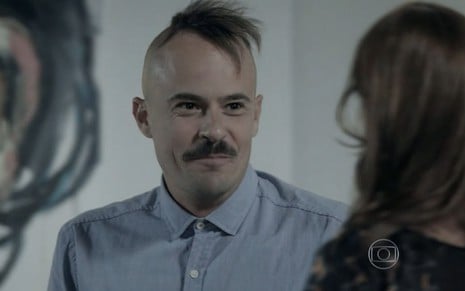 Paulo Vilhena grava com camisa azul, topete, bigode e expressão de felicidade como Salvador de Império, reprise da Globo