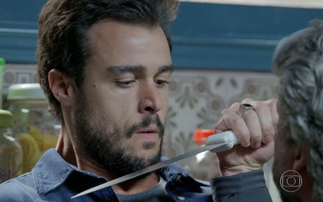Enrico (Joaquim Lopes) com uma faca no pescoço segurada por José Alfredo (Alexandre Nero) em cena de Império