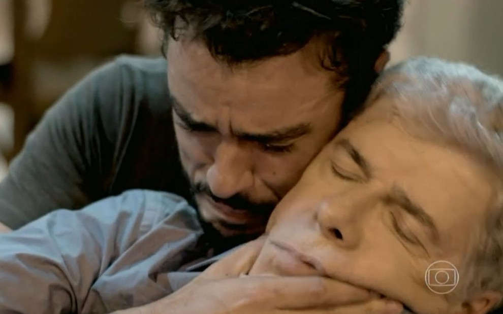 Cláudio (José Mayer) está desmaiado e é segurado por Enrico (Joaquim Lopes), que chora, em cena de Império