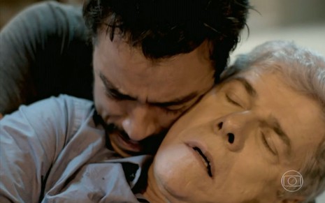 Cláudio (José Mayer) está desmaiado e é segurado por Enrico (Joaquim Lopes), que chora, em cena de ataque de Felipe (Laércio Fonseca)em Império