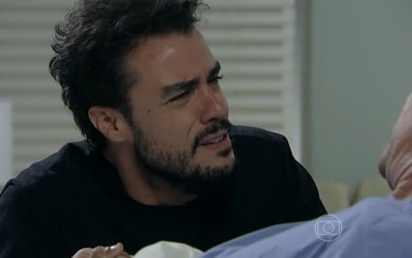 Enrico (Joaquim Lopes) chora agachado no leito de Cláudio (José Mayer) em cena de Império