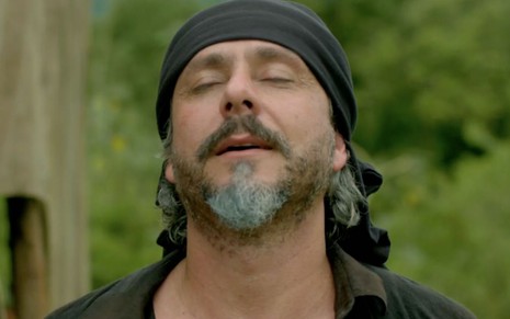 Alexandre Nero em cena de Império: personagem está caracterizado como José Alfredo, está de olhos fechados e com faixa preta no cabelo