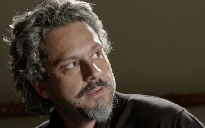 Alexandre Nero em cena de Império: caracterizado como José Alfredo, personagem olha com desconfiança para alguém fora do quadro
